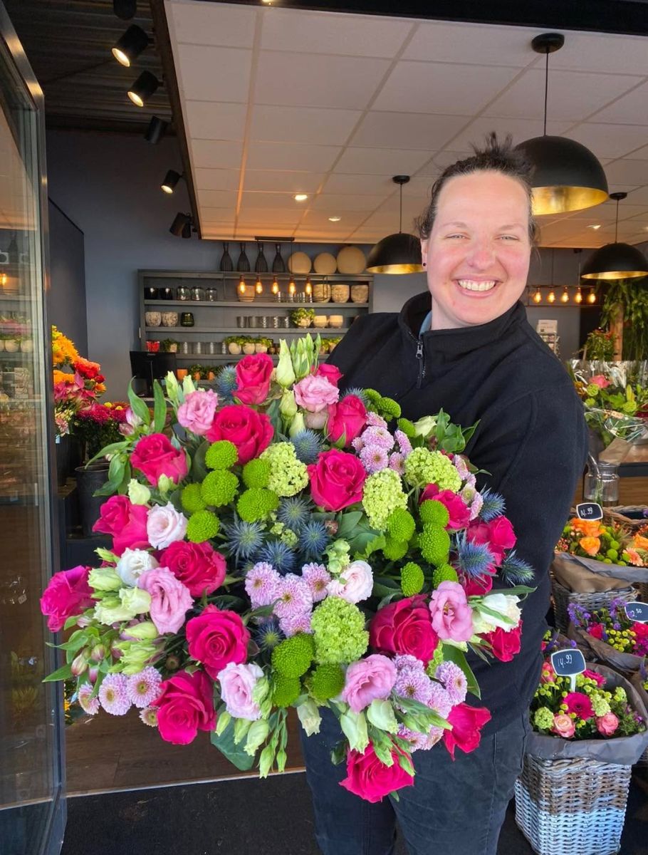Medewerker Mies Bloemen met een groot boeket roze groen en blauw