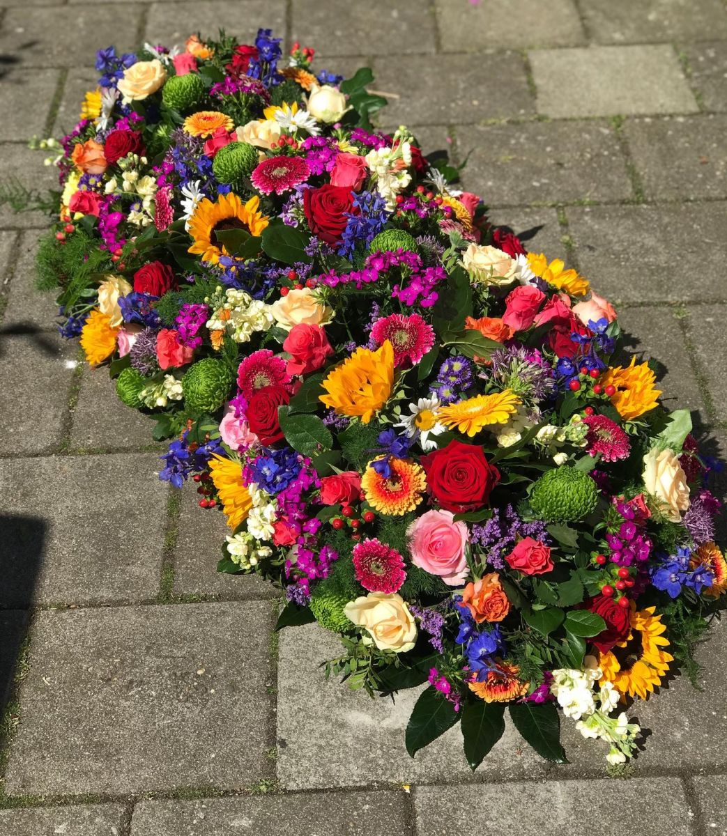 Kistbedekking rouwbloemstuk bonte kleuren Mies Bloemen