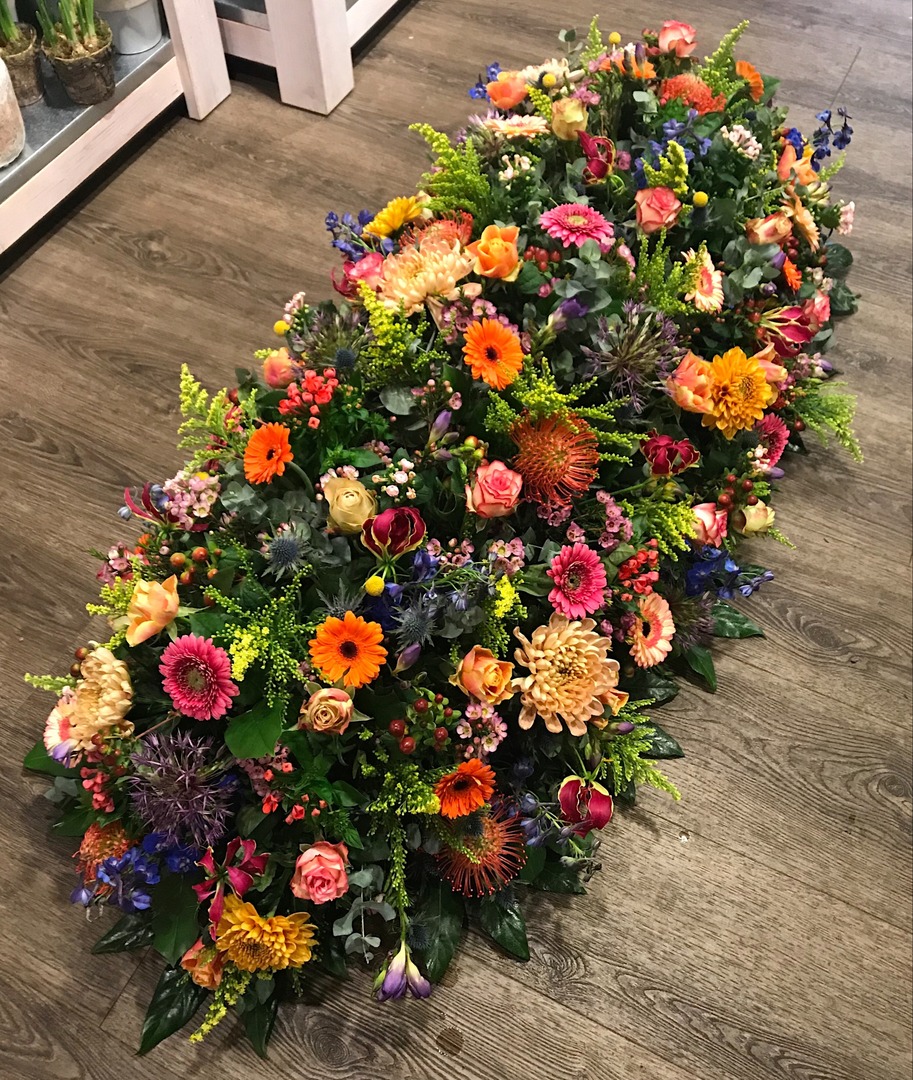 Kistbedekking rouwbloemstuk bonte kleuren Mies Bloemen